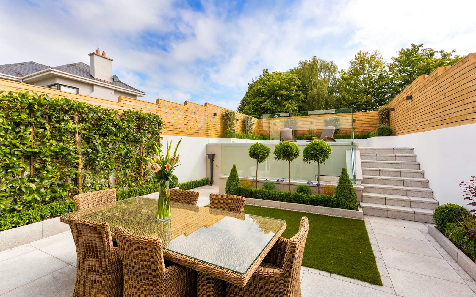 A contemporary courtyard garden with patio, lawn and topiary